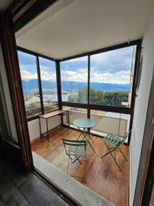 einen Balkon mit einem Tisch und Stühlen in einem Zimmer mit Fenstern in der Unterkunft Cozy 1-room apartment with veranda and parking in Font-Romeu