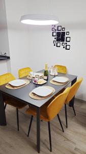 a table with yellow chairs and a black table with plates at Torre sol Penthouse - jacuzzi - AC - garage - pool in Pilar de la Horadada