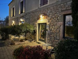 un edificio de piedra con una puerta y un banco delante en Appart Hotel Eugenie, en Louhans
