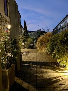 une passerelle en briques avec des plantes sur le côté d'un bâtiment dans l'établissement Appart Hotel Eugenie, à Louhans