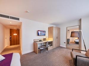 a hotel room with a desk and a bedroom at Park Regis Birmingham in Birmingham