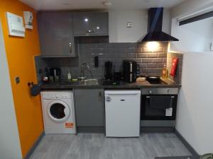 a kitchen with a sink and a washing machine at The Orange Outpost 8a - City Centre in Bradford