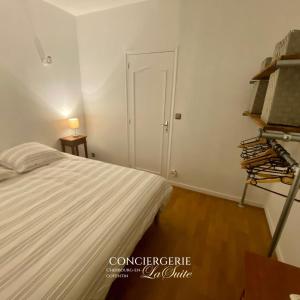 a white bedroom with a bed and a door at La Passerelle in Cherbourg en Cotentin