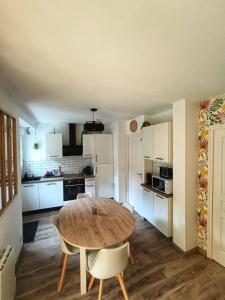 a kitchen with a wooden table and chairs in a room at Le Rez des Arcades - T2 en RDC hypercentre in Carentan