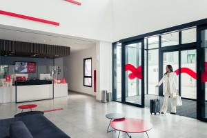 a woman walking through a room with glass doors at Hotel Moov Curitiba in Curitiba