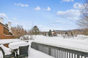 a snow covered patio with two chairs and a table at Stonybrook 22 in Stowe