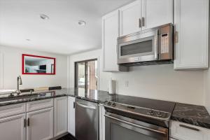 a kitchen with white cabinets and stainless steel appliances at Stonybrook 22 in Stowe