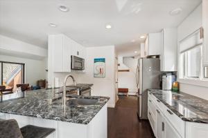 a kitchen with white cabinets and marble counter tops at Stonybrook 22 in Stowe