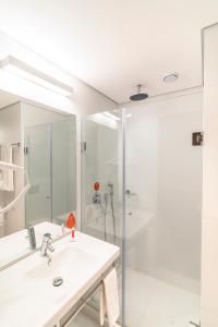a white bathroom with a sink and a shower at Hotel Moov Curitiba in Curitiba +26 photos