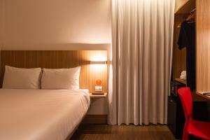 a hotel room with a bed and a red chair at Hotel Moov Curitiba in Curitiba