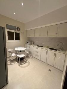 Una cocina con gabinetes blancos y una mesa en ella. en مذهله للوحدات السكنيه, en Muhayil