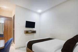 a bedroom with a bed and a tv on the wall at Hotel O Beverly Plaza Kurla in Mumbai
