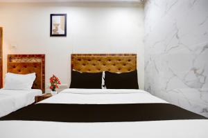 two beds in a hotel room with white walls at Hotel O Beverly Plaza Kurla in Mumbai