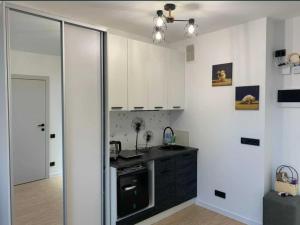 a kitchen with white cabinets and a black counter top at Lux Apartments in Truskavets