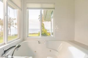 Grand Oceanfront Gated Estate on the Hamakua Coast في Hakalau: حمام أبيض مع حوض استحمام ونافذة +56 صورة