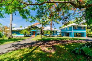 Grand Oceanfront Gated Estate on the Hamakua Coast في Hakalau: بيت ازرق فيه نخل وممر