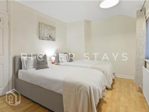 zwei Betten in einem weißen Zimmer mit einem Schild mit der Aufschrift „Bleibt“ in der Unterkunft Rustic 3BR house in Tilbury, Garden and Parking in Tilbury