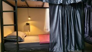 a bedroom with a bunk bed with blue curtains at Roameo, Varkala - A Cowork by The Hostel Stories in Varkala