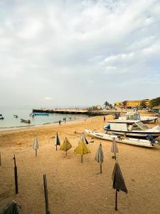 a sandy beach with umbrellas and boats on it at Maison Crespin in Dakar