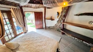 ein Schlafzimmer mit einem Bett in einem Zimmer mit Fenstern in der Unterkunft Tawaca SANCTUARY in Calabazo