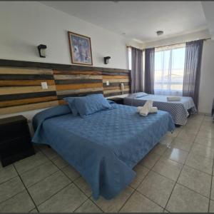a bedroom with two beds with blue comforters at Hotel Andalucía in Arica +20 photos