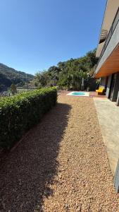 a gravel driveway next to a house with a hedge at Suíte Itaipava in Araras Petropolis