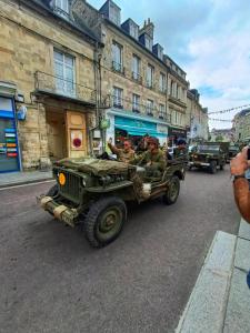 a group of men in a militaryruck driving down a street at Le Duplex des Arcades - T2 lumineux hypercentre in Carentan