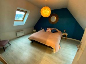 a bedroom with a bed and a blue wall at Le Duplex des Arcades - T2 lumineux hypercentre in Carentan