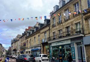 a busy city street with buildings and flags at Le Duplex des Arcades - T2 lumineux hypercentre in Carentan +1 photo