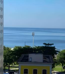 a yellow building with the ocean in the background at Lindo Sala Living com vista para o Mar in Santos
