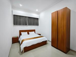 a bedroom with a bed and a wooden cabinet at Twins Hotel Boutique Syariah in Bandung