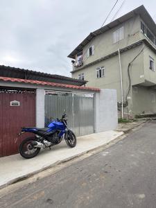 ein blaues Motorrad, das auf einem Bürgersteig neben einem Gebäude geparkt ist in der Unterkunft Casa em Angra dos Reis, no parque mambucaba in Angra dos Reis