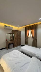 a large bedroom with two beds and a mirror at شقق يودج in Tabuk +5 photos