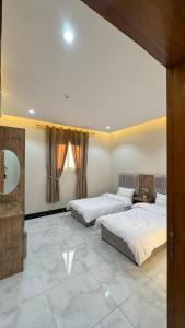 a bedroom with two beds and a mirror at شقق يودج in Tabuk
