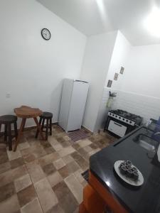 Una cocina con refrigerador, mesa y taburete. en Suíte Encanto do Paraíso - Cozinha - Self check-in, en Torrinha