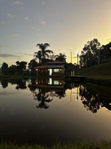 Una casa en un lago con la puesta de sol al fondo en Suíte Encanto do Paraíso - Cozinha - Self check-in, en Torrinha 11 fotos más
