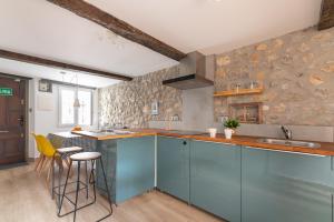 a kitchen with blue cabinets and yellow stools at La casa de Santa María in Laredo