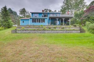 a blue house sitting on top of a lush green field at Charming Retreat with Deck about 4 Mi From Casco Bay! in Orrs Island