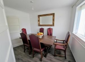 - une table à manger avec des chaises et une corbeille de fruits dans l'établissement Lovely 4 Bed Dudley Home, à Sedgley 2 autres photos