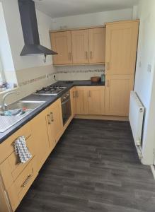 une cuisine vide avec des placards en bois et un évier dans l'établissement Lovely 4 Bed Dudley Home, à Sedgley