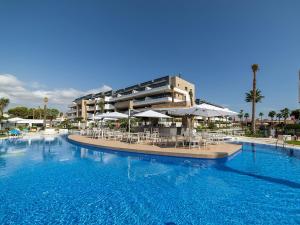 une grande piscine avec des chaises et des parasols en face d'un bâtiment dans l'établissement Modern and Luxury Apartment in Flamenca Village, à Orihuela Costa