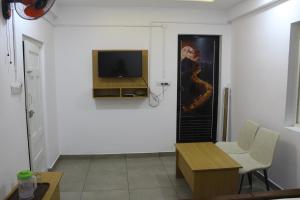 a living room with a tv on a white wall at Skyline Inn in Anachal