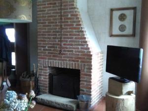 a brick fireplace with a television in a living room at Casa Rural El Montaraz de Gema in Gema