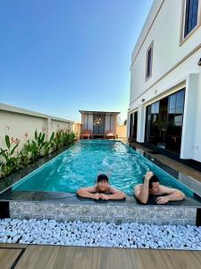 two people laying in a swimming pool in a house at Mimi Pool Villa Chiangmai in Chiang Mai