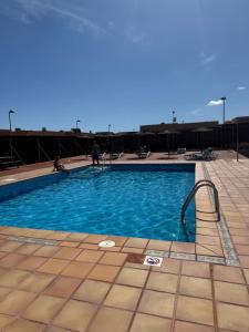 a swimming pool with blue water and a person in the background at CASA JAMACO, Corralejo in Corralejo