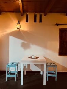 a white table with two chairs and a light on a wall at Amurasan beach studio in Tangalle