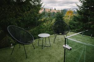 two chairs and a table in the grass at Oxygen Resort Cabin Hotels Lacu Rosu in Lacu Roşu