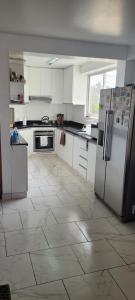 Il comprend une cuisine avec des appareils électroménagers blancs et du carrelage. dans l'établissement Bravos Hospedaje Punta Negra, à Punta Negra