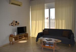 a living room with a couch and a tv at Chalou Stay - Comfort Near Athens Airport in Artemida