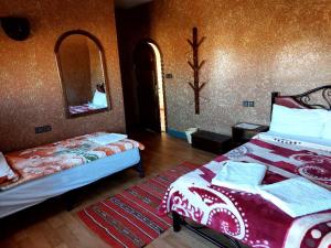 ein Schlafzimmer mit zwei Betten und einem Spiegel in der Unterkunft SUD-EST palace in Aït Igad